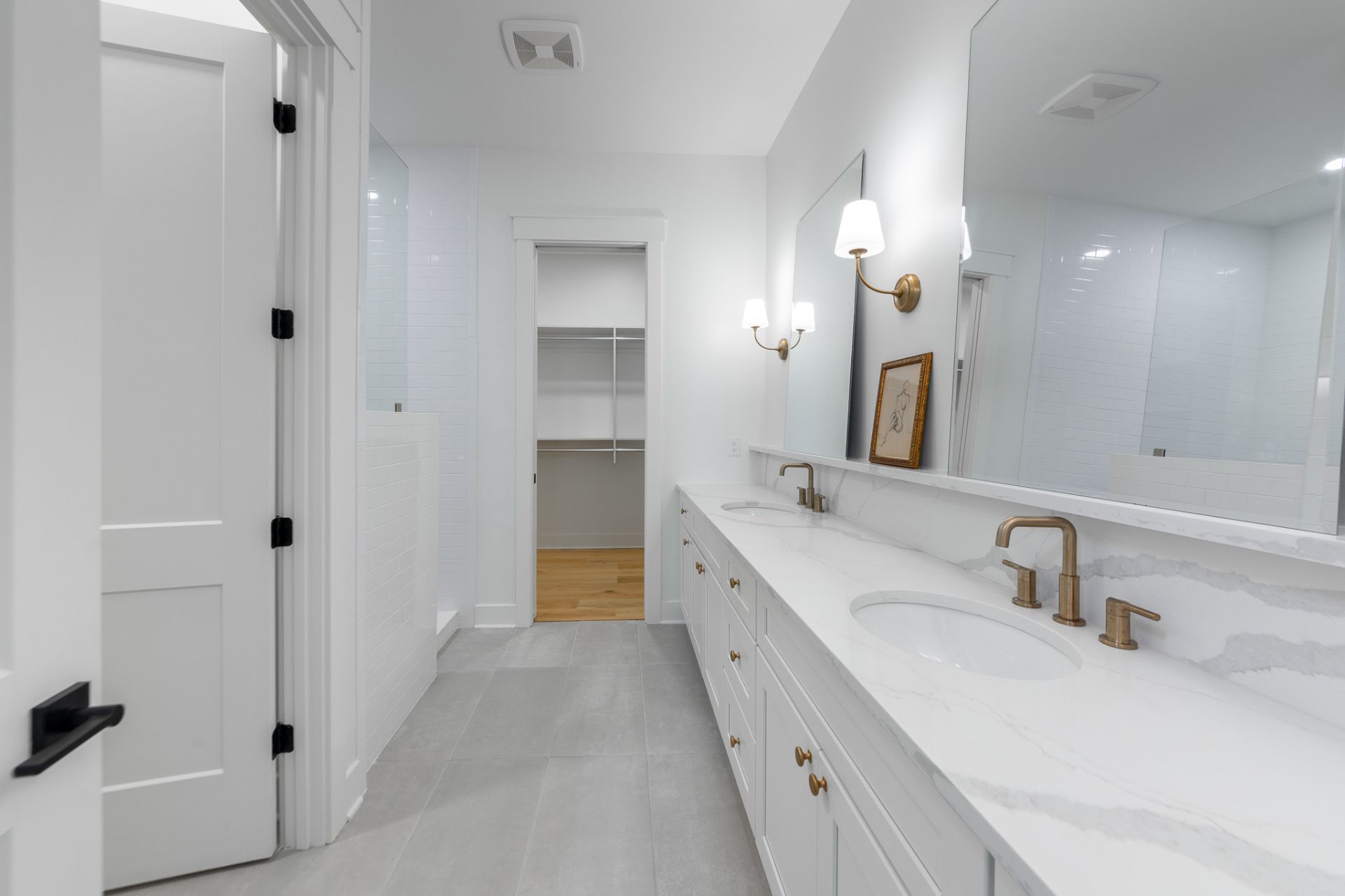 Primary bath with a marble double vanity and brushed brass fixtures